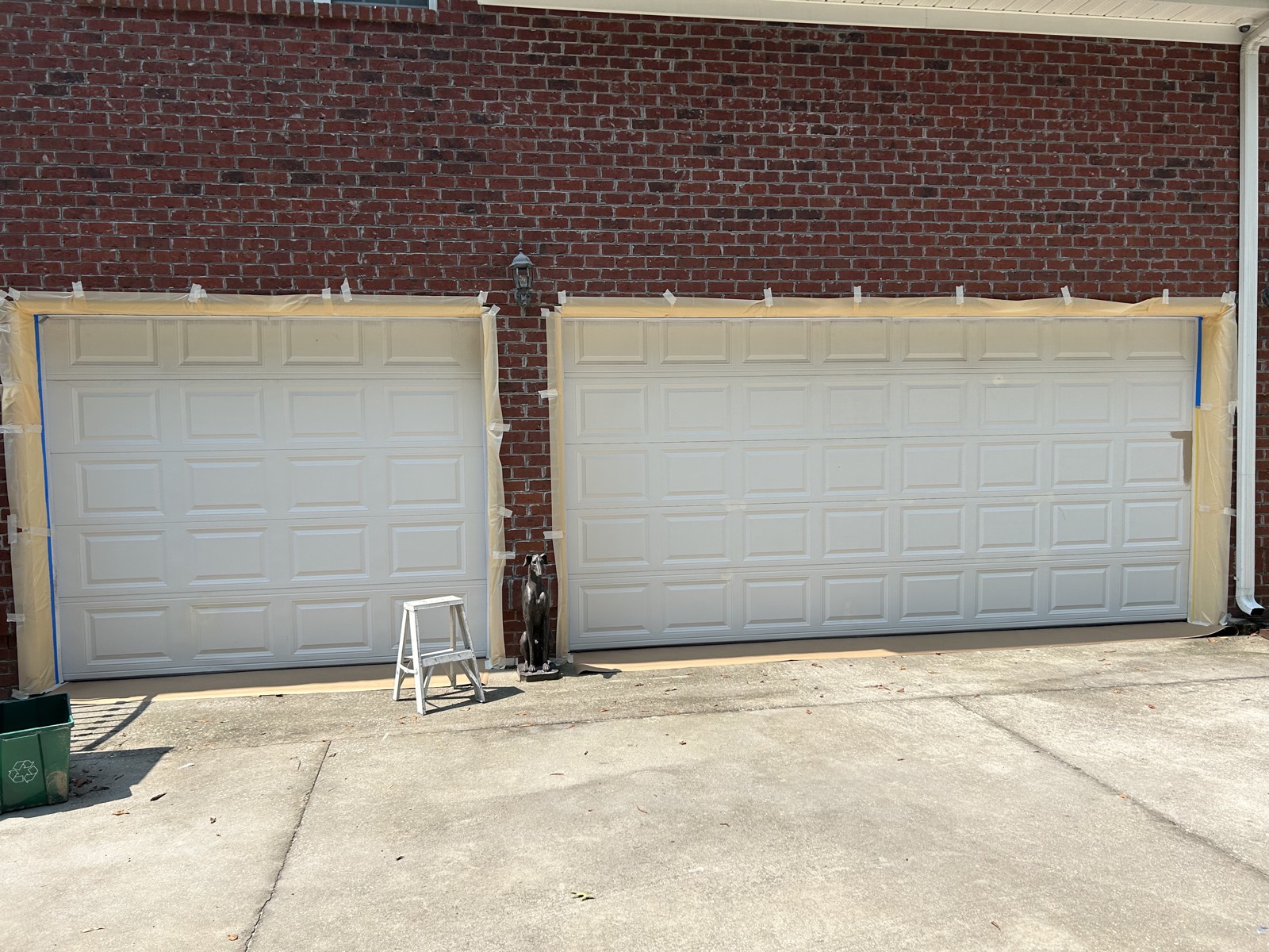 Two garage doors masked off before repainting in a light finish.