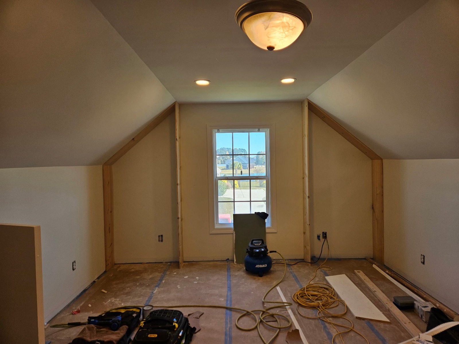 Unfinished upstairs wall around a window before built-in shelving and seating were added.
