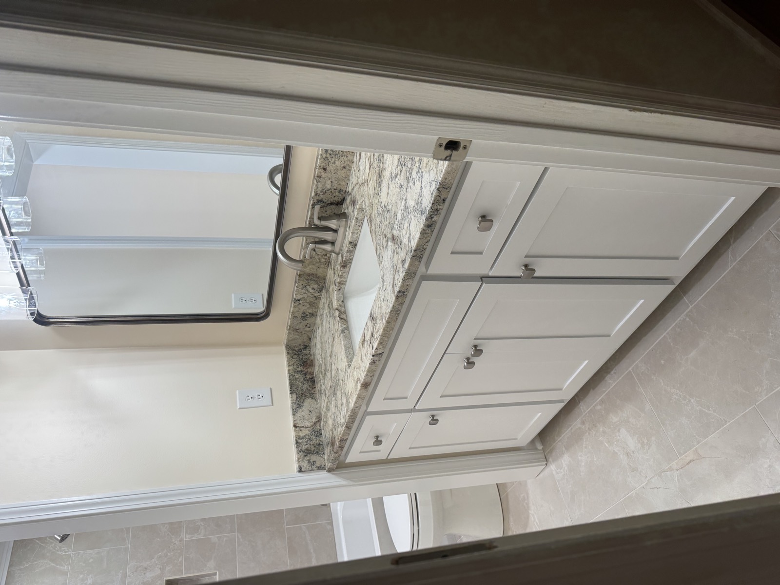 Updated bathroom vanity with painted cabinetry, stone countertop, and tile flooring.