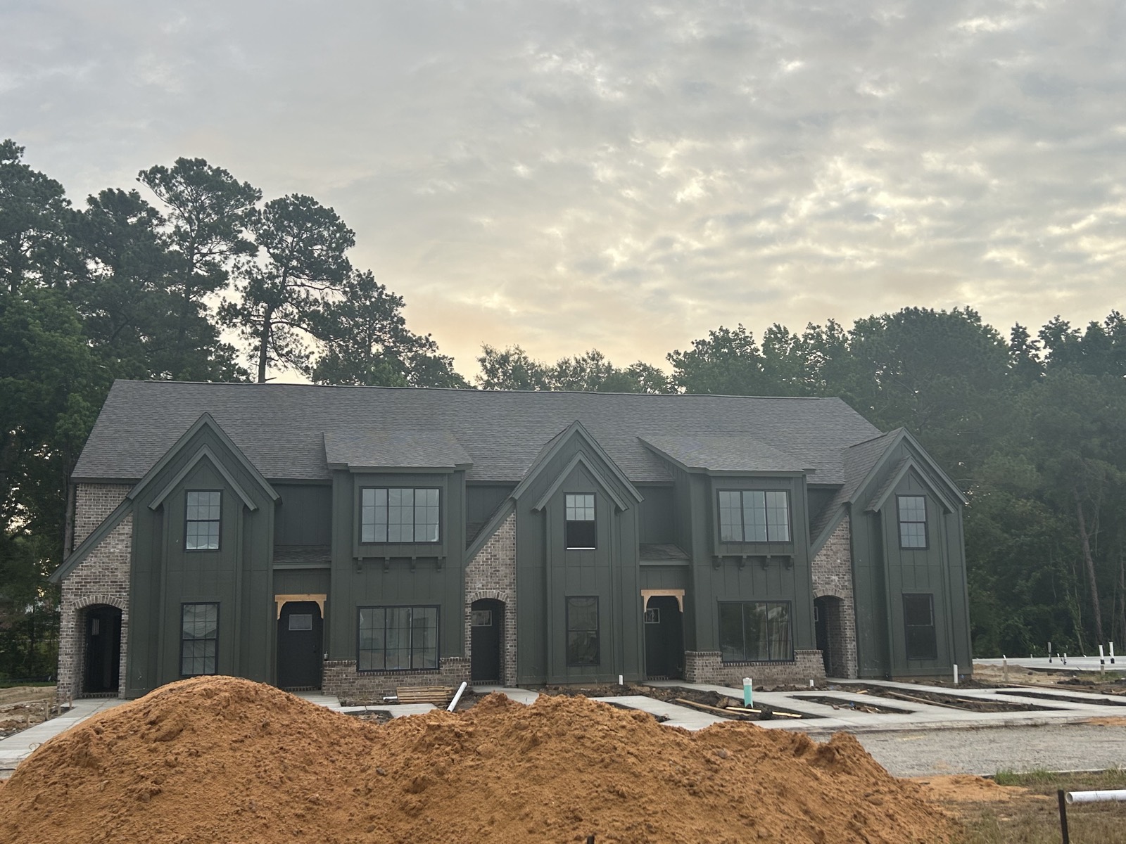 Apartment building exterior with deep green siding and brick accents.