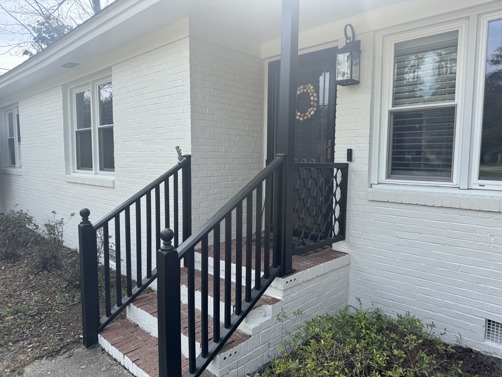 Front porch with white painted brick, black railings, and black front door accents.