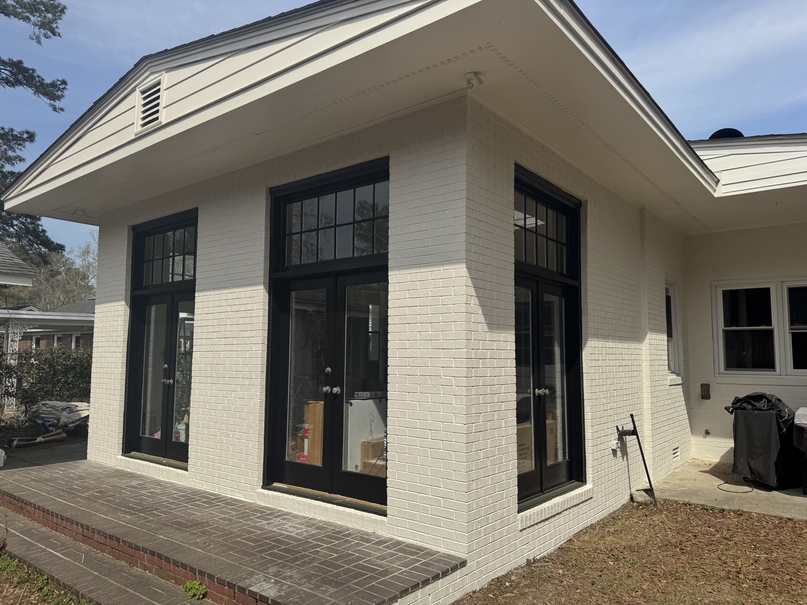 White painted brick exterior with black-framed doors and windows.