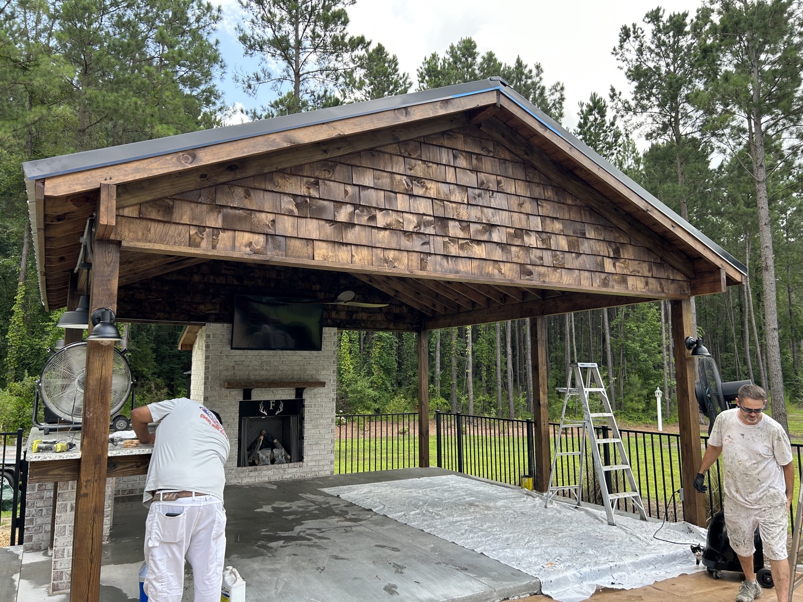 Custom outdoor pavilion with stained wood framing, fireplace, and patio space.